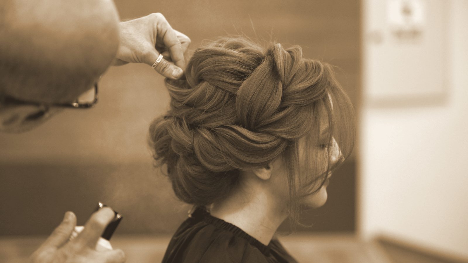 Stylista wpina pasma w upięcie z grubego warkocza.